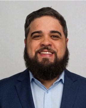 Portrait of Angel Martínez, smiling, in a navy blazer